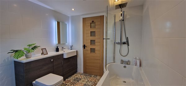 main bathroom with toilet, washbasin, bath with shower over and vanity mirror with lights